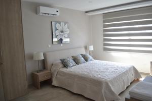 a white bedroom with a bed with blue pillows at Marianna Hotel Apartments in Limassol