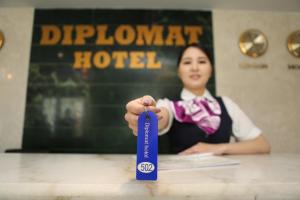 a woman is holding up a blue ribbon at Diplomat Noble Hotel in Ulaanbaatar