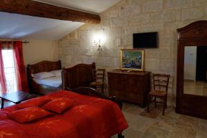 um quarto com uma cama, uma secretária e uma televisão em Le Mas d'Isnard em Arles