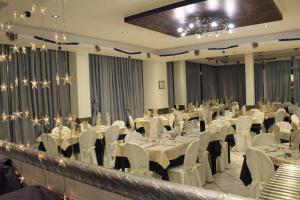 un salón de banquetes con mesas blancas y sillas blancas en Hotel Margherita en Rímini
