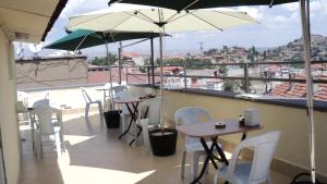 un patio con mesas, sillas blancas y sombrillas en Yavuz Hotel, en Ankara