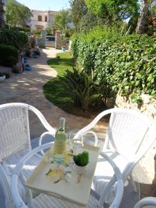 a white table with a bottle of wine and a plant on it at Villa La Chiocciola in San Vito lo Capo