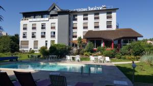 un hôtel avec une piscine en face d'un bâtiment dans l'établissement Kyriad Bourg En Bresse, à Bourg-en-Bresse