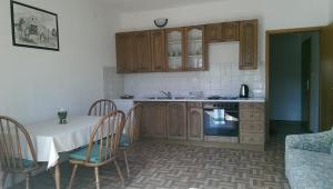 a kitchen with wooden cabinets and a table with chairs at Apartmani Ledenko in Kaštela
