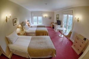 a hotel room with two beds and a desk at Donnington Grove in Newbury