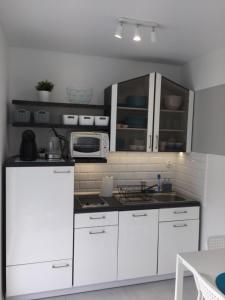 a kitchen with white cabinets and a microwave at Apartament z widokiem na morze in Międzyzdroje