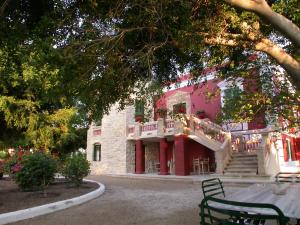 a large pink building with a balcony and stairs at Archontiko Angelou in Alinda