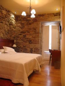 1 dormitorio con cama y pared de piedra en Hotel Casa de Caldelas, en Castro Caldelas