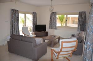 sala de estar con sofá, sillas y TV en Anthorina Villa 6 en Protaras