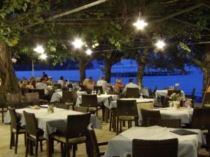 a restaurant with tables and chairs with people sitting at them at Dassia Beach Hotel in Dassia