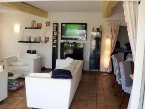 a living room with white furniture and a flat screen tv at Le Jardin d Eden in Sainte-Maxime