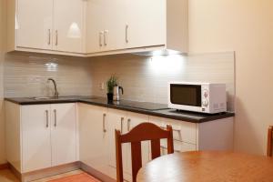 a kitchen with white cabinets and a microwave and a table at Casa Rosa in Leiria