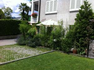 un jardín frente a una casa con sombrilla en Casa al Lido, en Locarno