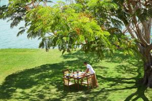 un homme assis à une table sous un arbre dans l'établissement Jetwing Lagoon, à Negombo