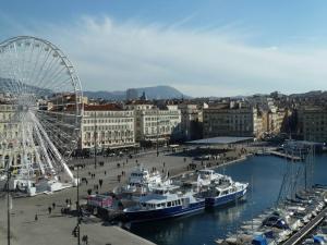 a ferris wheel and boats in a harbor with a city at Studio in Marseille