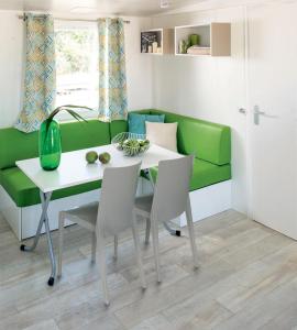 a living room with a green couch and a table and chairs at Giannella Camping in Orbetello