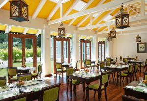a dining room with tables and chairs and windows at Jetwing St Andrew's in Nuwara Eliya