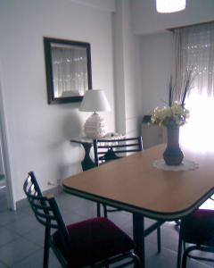 una mesa de comedor con sillas y un jarrón con flores. en temporario la plata centro balcon al frente en La Plata