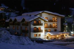 a large building with snow on it at night at Hotel Franco in Andalo