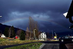 Ein Regenbogen am Himmel über einer Straße mit einem Auto in der Unterkunft Lyngseidet Gjestegård in Lyngseidet