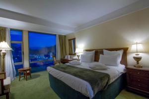 um quarto de hotel com uma cama grande e uma janela grande em Hotel HP Tower One Brasov em Braşov