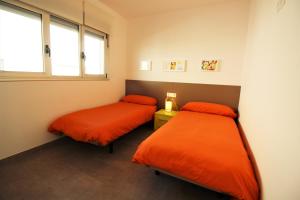 サン・ペドロ・デル・ピナタルにあるVilla Alegreのオレンジのシーツが備わる客室内のベッド2台