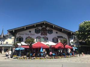 people sitting outside of a restaurant with umbrellas at Hotel Alte Post in Oberammergau