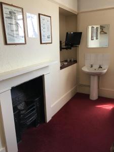 a room with a fireplace and a sink and a tv at The Bridge Inn in Isleworth