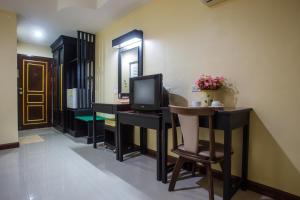 Habitación con TV, mesa y espejo. en Monrawee Pavilion Resort, en Phitsanulok