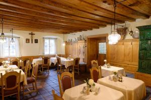 a restaurant with white tables and chairs and wooden ceilings at Hotel Alte Post in Oberammergau