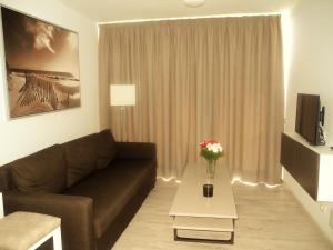 ein Wohnzimmer mit einer Couch und einem Tisch mit Blumen in der Unterkunft Apartamentos Los Mocanes in Puerto Rico de Gran Canaria