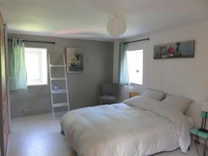 a bedroom with a large white bed and two windows at Chambres d'hôtes - B&B in Gétigné