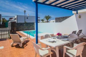 eine Terrasse mit einem Tisch, Stühlen und einem Pool in der Unterkunft Villa Aitonita in Playa Blanca