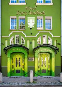 マルボルクにあるHotel Stary Malborkの緑の建物(4つのドア付)とホテルステイマロワ