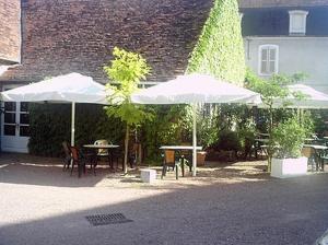 a patio with tables and umbrellas in front of a building at Logis hotel Saint-Joseph in Sancoins