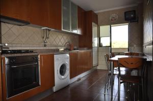 a kitchen with a washing machine and a table with chairs at Apartamento Algarve Holidays in Faro