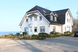 a large white house with a black roof at Waldpavillon in Fehmarn