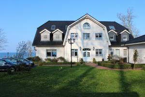 a large white house with a car parked in front of it at Waldpavillon in Fehmarn