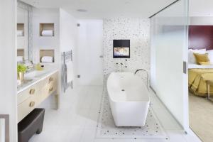 a white bathroom with a tub and a bed at Mandarin Oriental, Paris in Paris