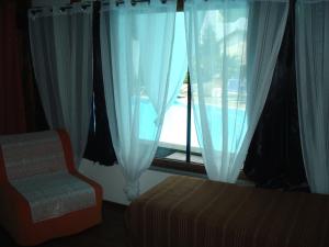 ein Schlafzimmer mit einem Fenster mit einem Bett und einem Stuhl in der Unterkunft Residenza Le Palme in Caltignaga
