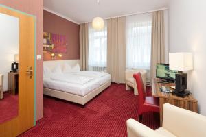ザンクト・ペルテンにあるシュタットホテル ハウザー エックの白いベッドとテレビが備わるホテルルームです。