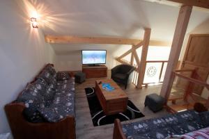 a living room with a couch and a tv at Les Chalets Du Grand Galibier in Valloire