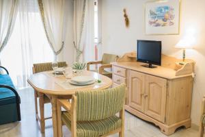 sala de estar con mesa y TV. en Jardín de Mariote Apartment, en Almuñécar