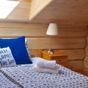 Dormitorio con cama con almohada azul y lámpara en Eco-House Ainaži, en Ainaži