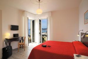 a bedroom with a red bed and a desk and a window at Hotel Tirreno in Alassio
