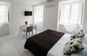 a bedroom with a bed and a table and windows at DOMO Apartments - Trieste Goldoni in Trieste