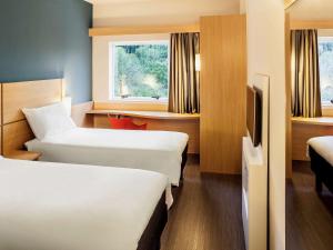 a hotel room with two beds and a television at ibis Juiz de Fora in Juiz de Fora