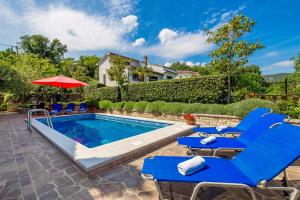 einen Pool mit blauen Liegestühlen und einem Sonnenschirm in der Unterkunft Apartments Dalia in Lovran
