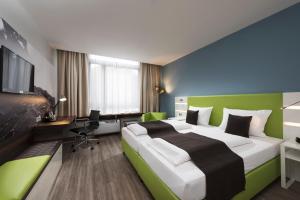 a hotel room with a large bed and a desk at ibis Styles Offenburg City in Offenburg