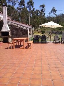 patio ze stołem, parasolem i krzesłami w obiekcie Casa Portomeiro w mieście San Román